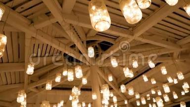 易拉罐自制的灯笼悬挂在木制的天花板上，发光发亮.. 相机在固定装置周围移动